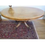 A Victorian burr walnut tilt top oval breakfast / dining table, on turned and carved column and