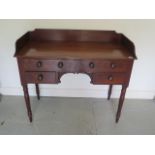 A Georgian mahogany 4 drawer washstand / side table with a shaped upstand standing on turned legs,