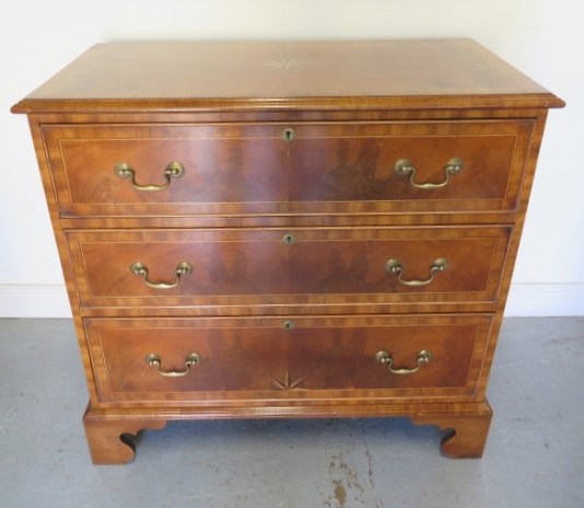 A reveneered 3 drawer chest with star inlay, standing on shaped bracket feet, 90cm tall x 95cm x