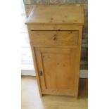 A stripped pine clerks desk / podium with a slope above a drawer and cupboard, 120cm tall x 57cm x