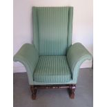 A mahogany upholstered mahogany wingback chair with exaggerated scroll arms, 116cm tall x 87cm wide,