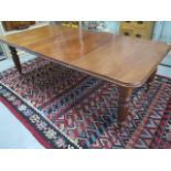 A 19th century mahogany wind out dining table with 2 leaves on turned reeded legs, 73cm tall,