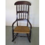 An early 19th century rush seated and spindle back rocking chair, 112cm tall