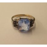 A white metal ring set with a blue stone possibly aquamarine, 10mm x 8mmx 5mm, the shoulders set