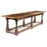 A CHARLES II OAK REFECTORY TABLE DATED '1673' the boarded top with cleated ends, the frieze carved