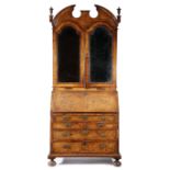 A GEORGE II WALNUT BUREAU BOOKCASE C.1730 cross and feather banded, the broken arch cornice with