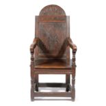 AN OAK PANELLED BACK OPEN ARMCHAIR 17TH CENTURY AND LATER the arched top carved with an urn