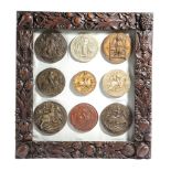 NINE PLASTER MEDIEVAL STYLE SEALS mounted in a glazed walnut frame, carved with fruits, leaves and