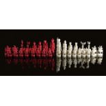 λ A CHINESE EXPORT CARVED IVORY FIGURAL CHESS SET MID-19TH CENTURY natural and stained red, the