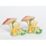 A pair of Clarice Cliff Gnome book ends, each modelled resting underneath a toadstool, painted in