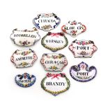 A collection of ten enamel wine labels, including a pair of shaped form, with ribbon and foliate