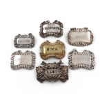 A collection of seven early 19th century silver wine labels, shaped rectangular form, vine, shell