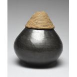 A Zulu jar South Africa blackware of globular form with a basketry domed cover, 18cm high. (2)