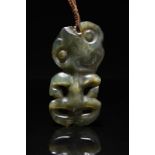 A Maori hei-tiki pendant New Zealand nephrite, with a large tilted head having worn features and