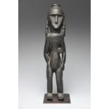 A Timor standing figure Indonesia with a top knot and long earrings relief carved lizards, and