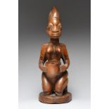 A Yoruba cup bearer Nigeria the kneeling female figure with a quadripartite and domed coiffure and