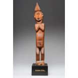 A Nias male figure Indonesia with a stylised palm crest and a scroll back knot, the face with a