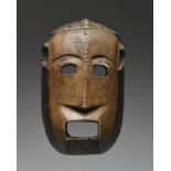 A Makonde mask Tanzania with a linear carved coiffure and beard and with black and brown pigment,