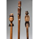 A South African staff carved with a male figure wearing a peaked flat cap and with large ears,