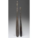Two Irian Jaya sago stirrers Indonesia with carved stylised decoration, 63cm and 78cm long. (2)