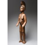 An Igbo female alusi figure Nigeria with a swirled crested coiffure and with facial and body