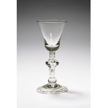 A baluster wine glass, c.1715, the bell bowl raised on a baluster stem with triple annulated central