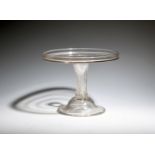 A tall glass tazza, c.1740, the circular top with galleried rim, raised on an inverted baluster stem
