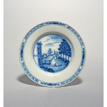 A delftware plate, c.1760-80, the well painted in blue with two figures crossing an arched bridge