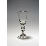 A baluster wine glass, c.1720, the deep round funnel bowl raised on a stem comprising an inverted