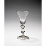 A baluster wine glass, c.1730-35, with a generous bell bowl raised on a baluster stem with two