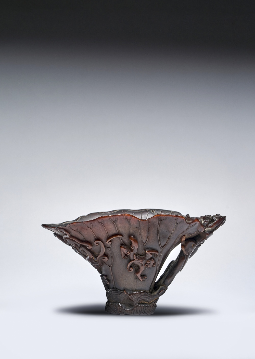 A CHINESE RHINOCEROS HORN 'LOTUS LEAF' LIBATION CUP 17TH CENTURY Modelled as a curly lotus leaf with