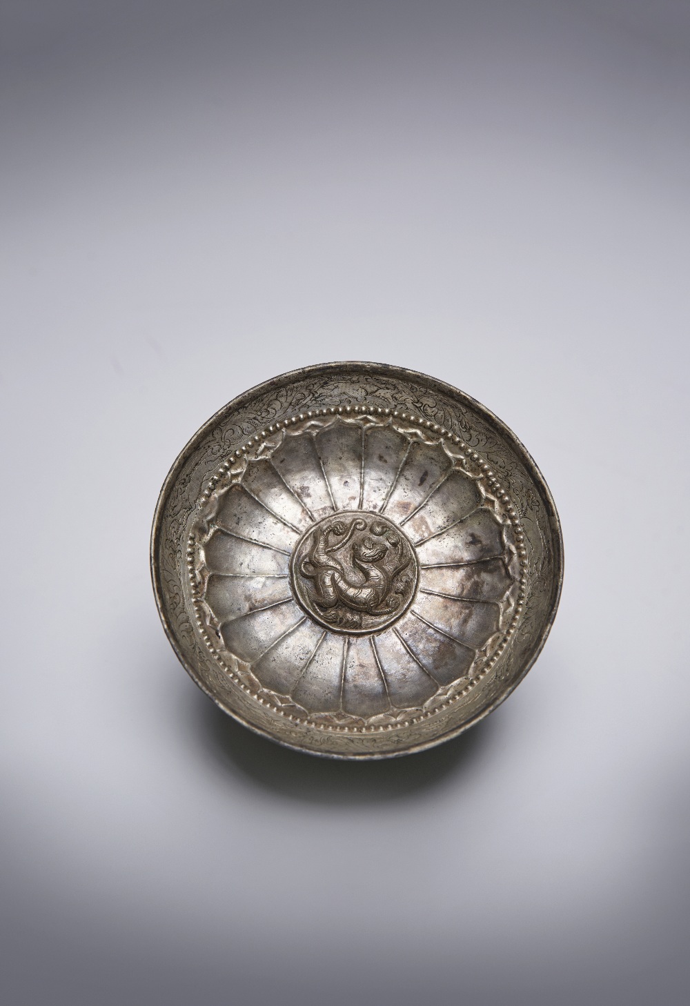 A CHINESE SILVER REPOUSSE 'TIGER' BOWL SIX DYNASTIES The shallow bowl raised upon a flared foot,