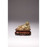 A CHINESE CARVED SOAPSTONE FIGURE OF BUDAI 18TH CENTURY The reclining deity with his face carved
