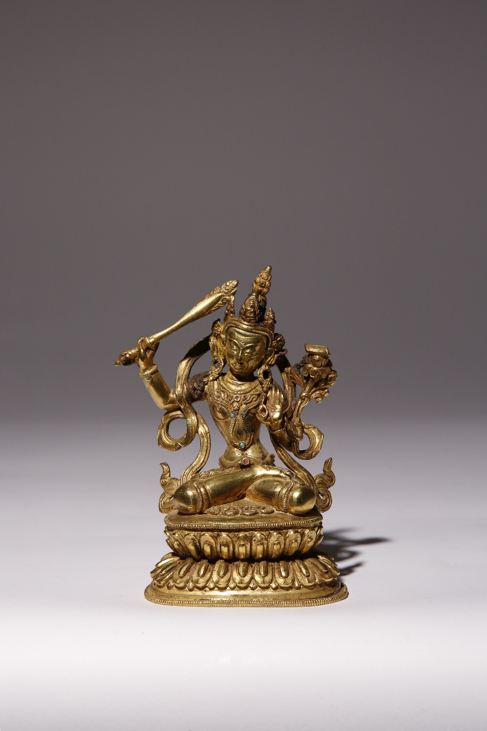 A TIBETAN GILT-BRONZE FIGURE OF MANJUSRI 15TH/16TH CENTURY Seated in dhyanasana upon a double
