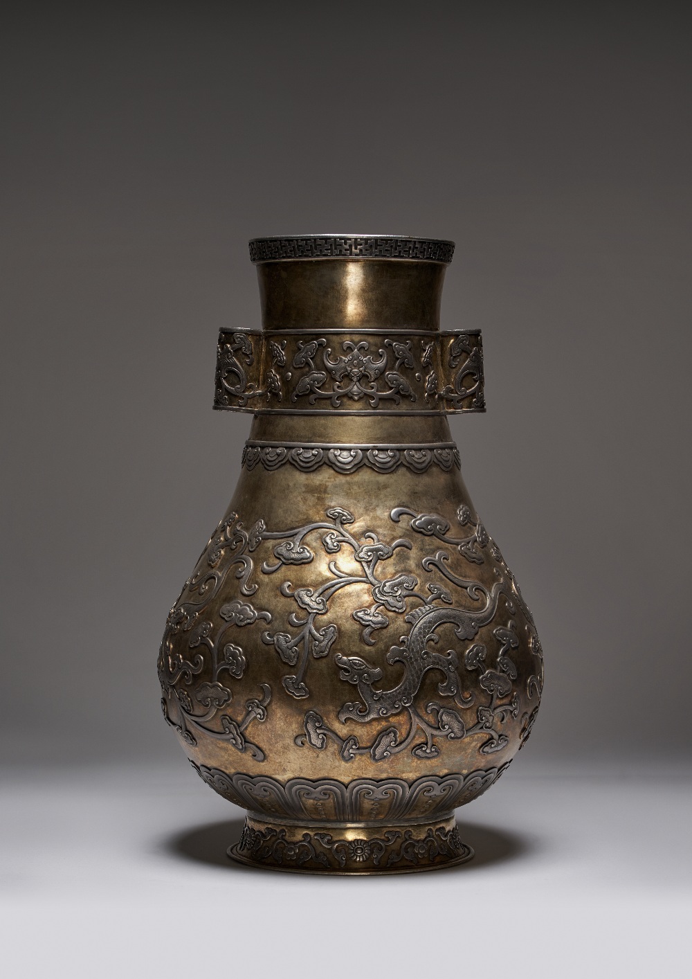 A LARGE CHINESE SILVER AND PARCEL-GILT VASE, HU PROBABLY QING DYNASTY The body decorated in relief