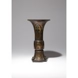 A CHINESE ARCHAISTIC PARCEL-GILT BRONZE GU-SHAPED VASE 17TH CENTURY Cast with taotie masks against a