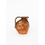 A Martin Brothers stoneware face jug by Robert Wallace Martin, dated 1903, modelled in low relief to