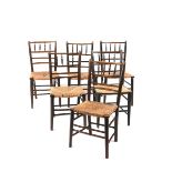 Six ebonised wood Sussex style chairs, possibly retailed by Liberty & Co, with bobbin backs, rush