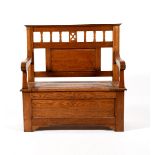 An oak hall settle, rectangular section with hinged cupboard seat, plank back below decorative