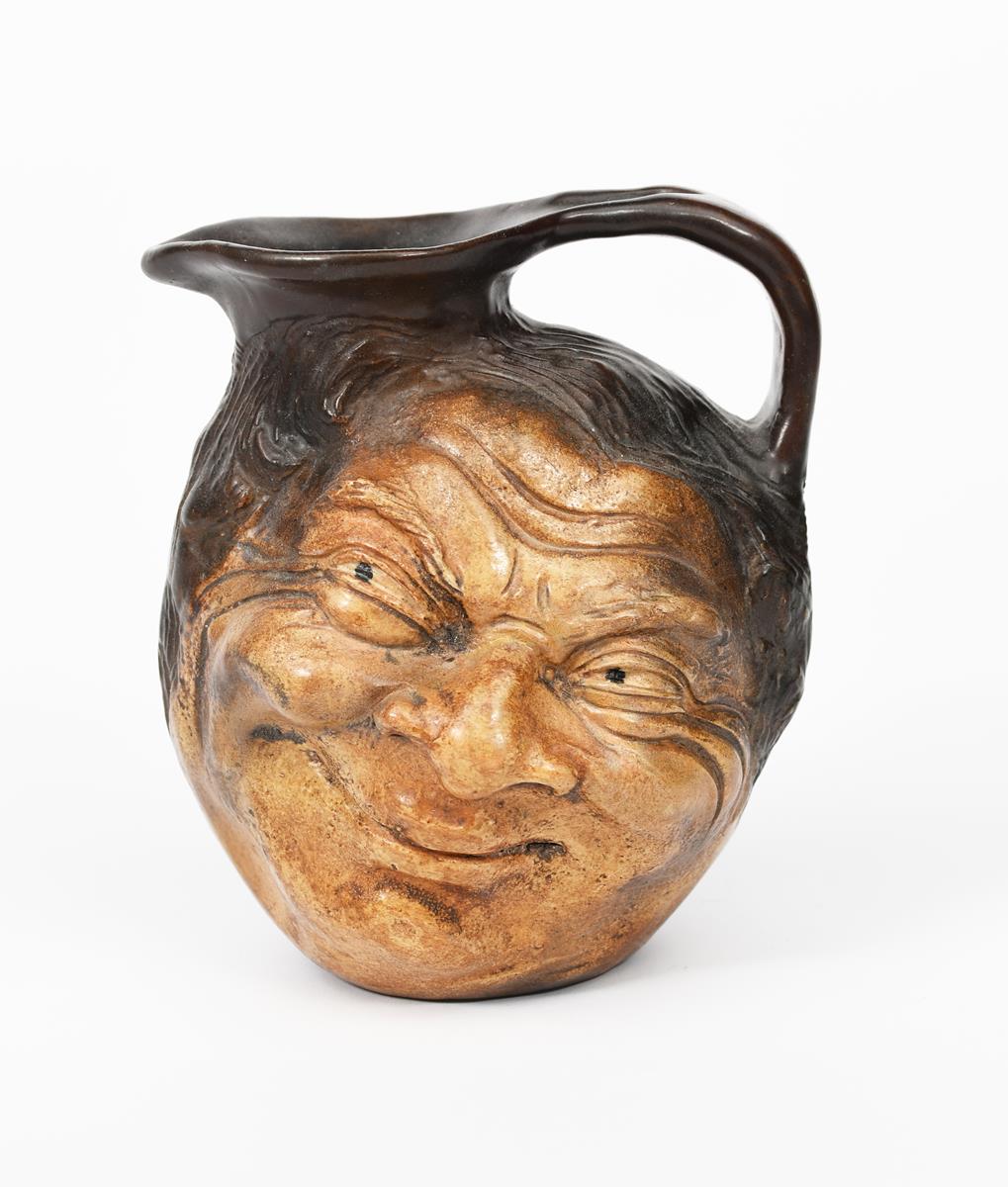 A Martin Brothers stoneware face jug by Robert Wallace Martin, modelled in relief with a smiling