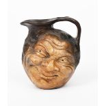 A Martin Brothers stoneware face jug by Robert Wallace Martin, modelled in relief with a smiling