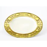 A lacquered brass wall mirror in the manner of the Newlyn Industrial Classes, oval, stamped with a