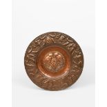 A repousse hammered copper charger probably by John Pearson, the broad rim hammered with a frieze of