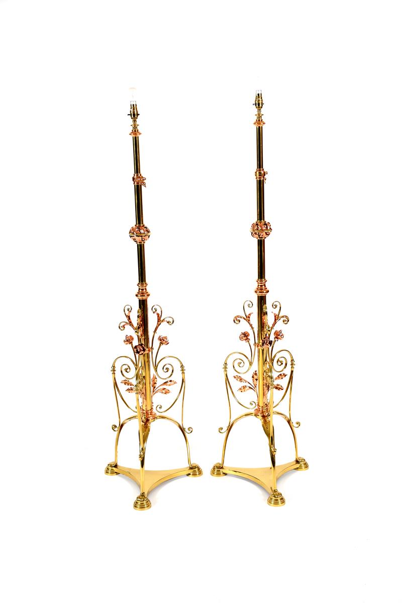 A pair of Hinks & Sons copper and brass adjustable floor lamps, tripod feet, scrolling foliate frame
