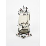 A silver mounted glass tankard and cover, swollen low base on four tapering, scrolled feet, cast
