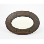 An elliptical stained wood wall mirror probably Irish, the wooden frame carved with geometric