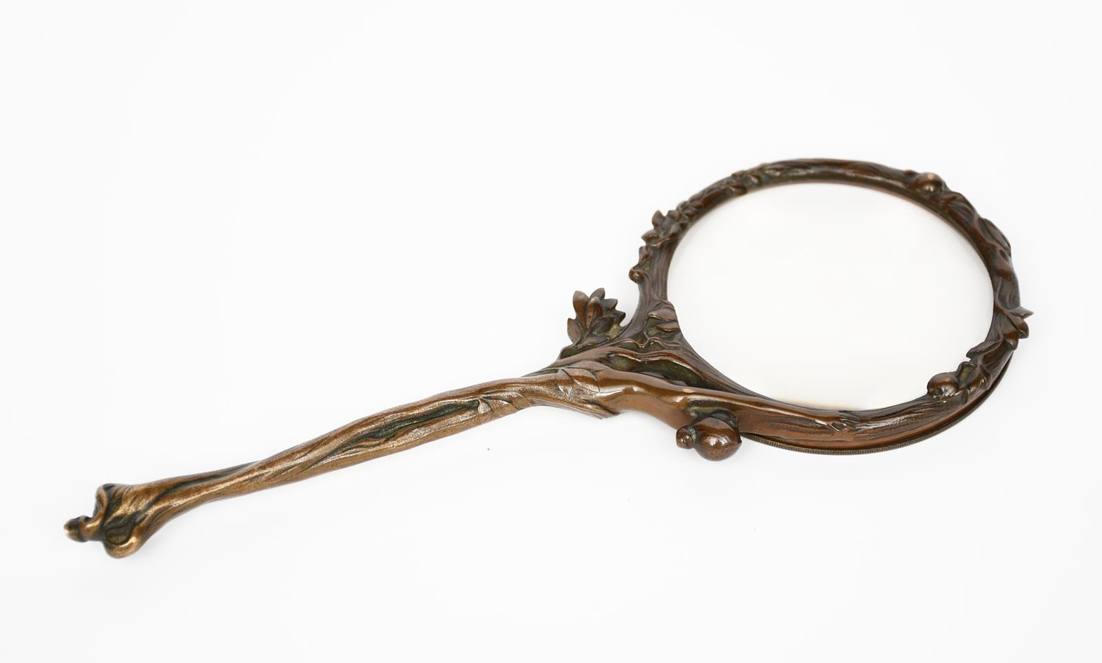 An Art Nouveau patinated bronze magnifying glass, cast with a lady issuing from foliage, and