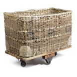 A LARGE WICKER LOG BASKET MID 20TH CENTURY with a platform base and iron spoke wheels 90.2cm high,