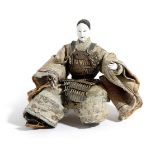 A JAPANESE SAMURAI DOLL 19TH CENTURY with glass eyes and a lacquered head, in a kneeling posture,