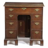 A GEORGE II OAK KNEEHOLE DESK C.1730-40 with a caddy moulded edge top above an arrangement of
